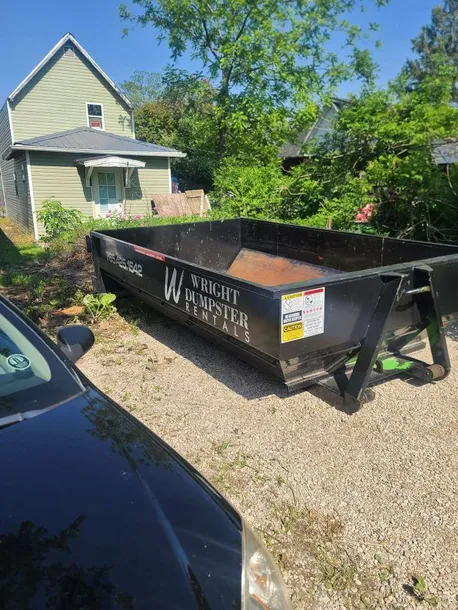 Black roll-off dumpster from wright dumpster on a gravel