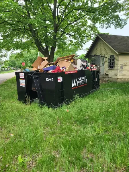 A black 15-yard dumpster from Wright Dumpster Rentals, filled with various discarded items